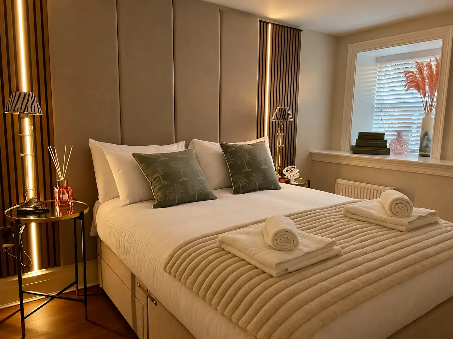 Bedroom with a panelled headboard, lit slatted wood panels and zebra-print lamps