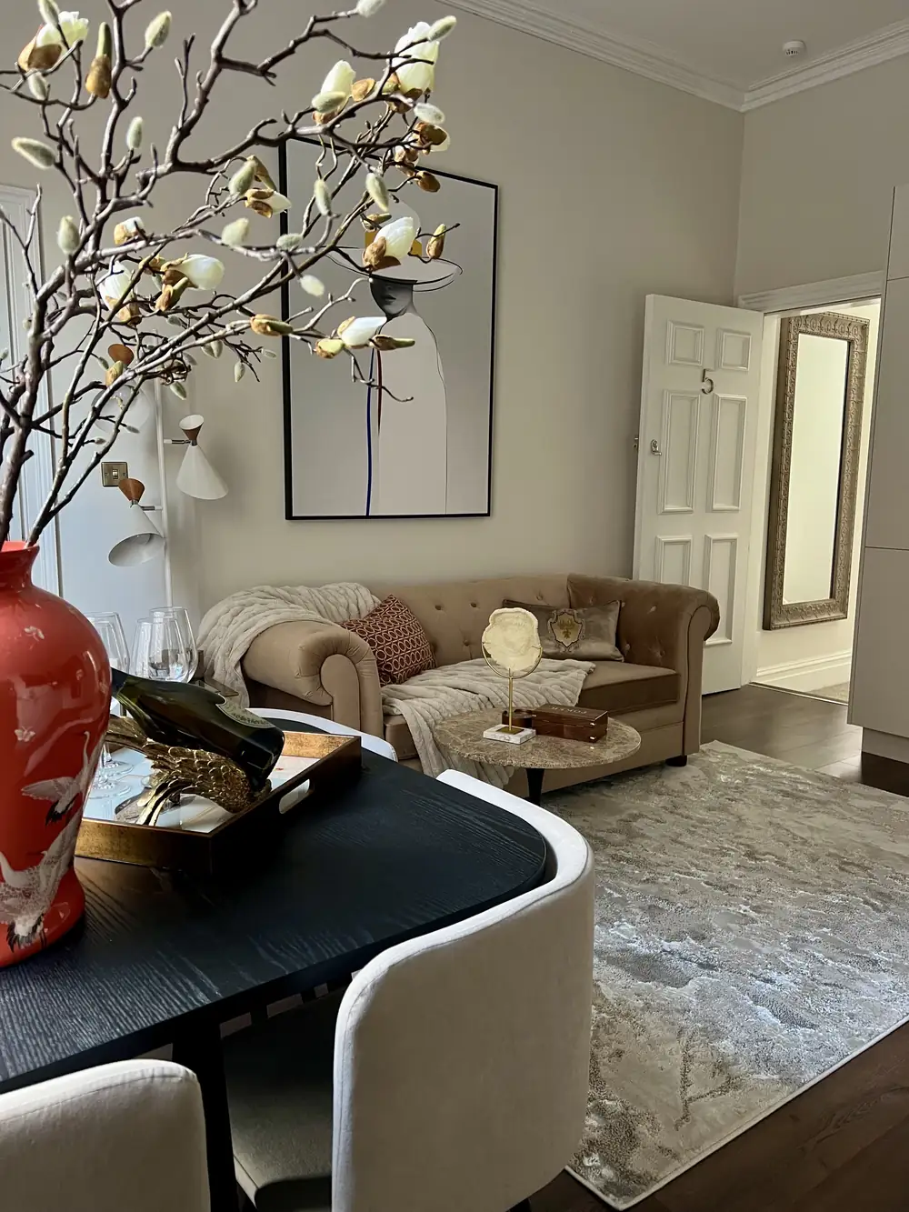 Lounge with a red vase, round dining table and chesterfield sofa