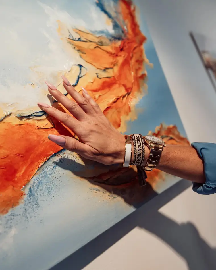 Dannielle's hand resting on the textured surface of a painting