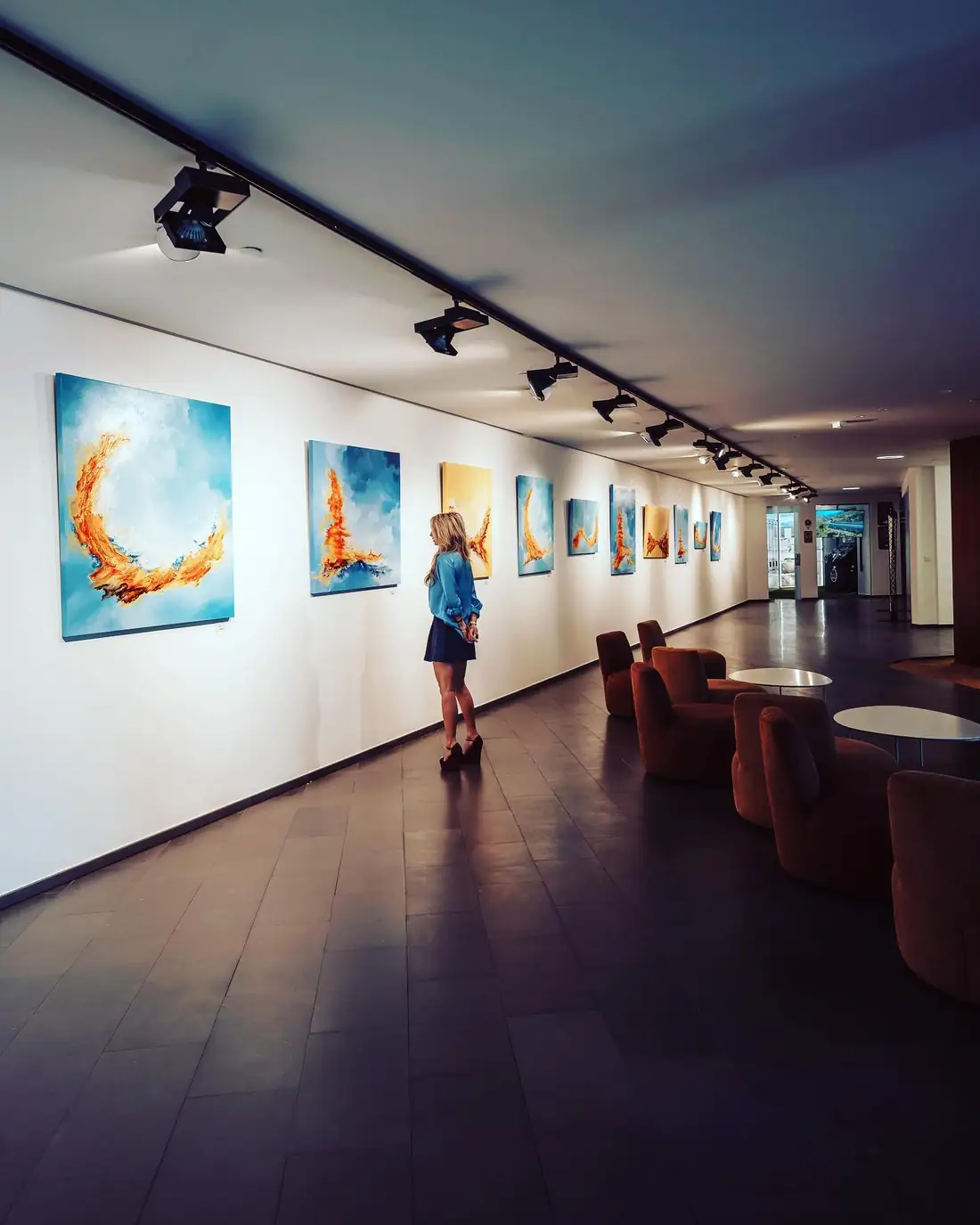 The exhibition wall at Baobab Suites, a long gallery hung with Dannielle's paintings