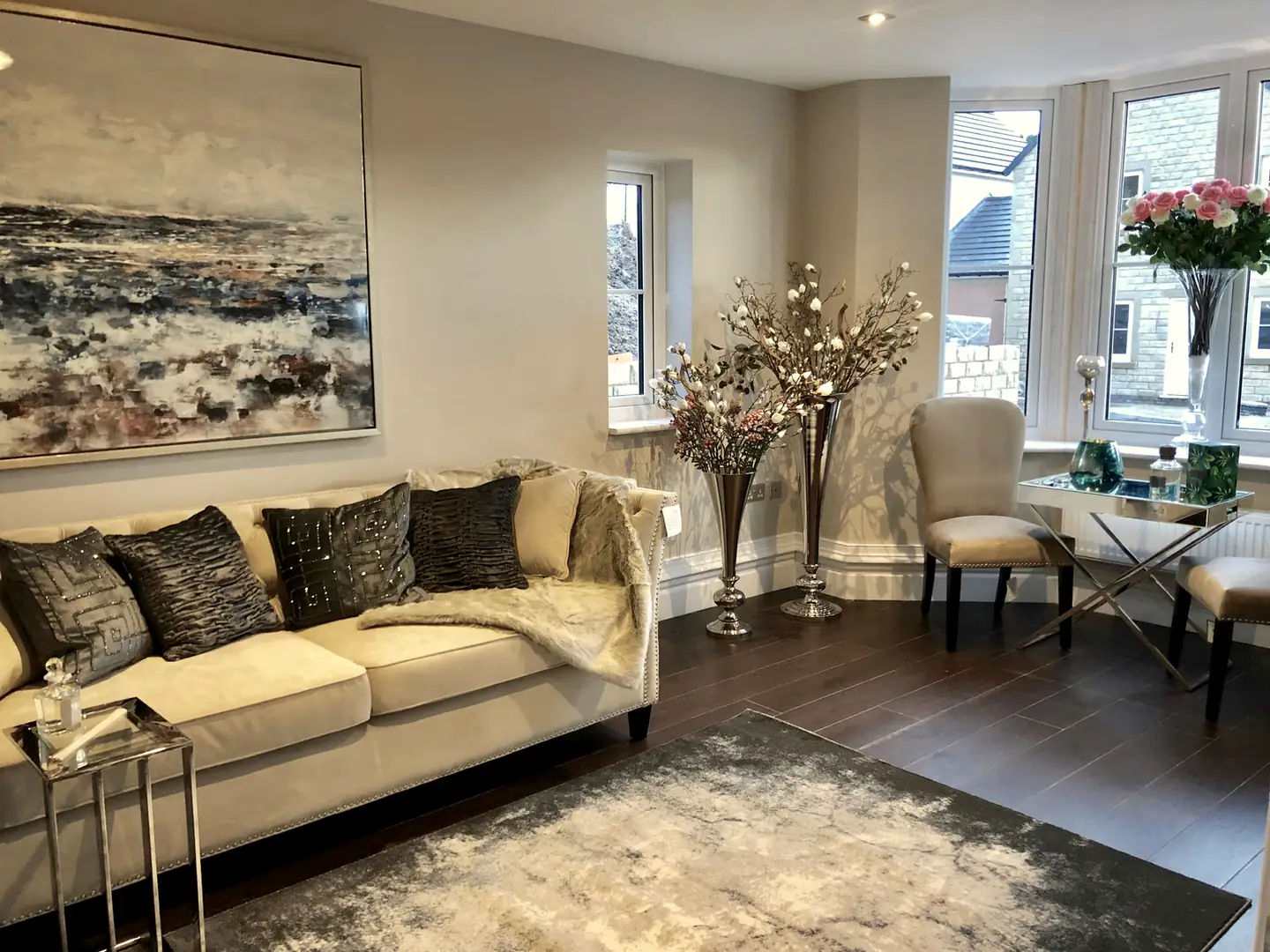 Show home living room with a cream sofa and seascape painting