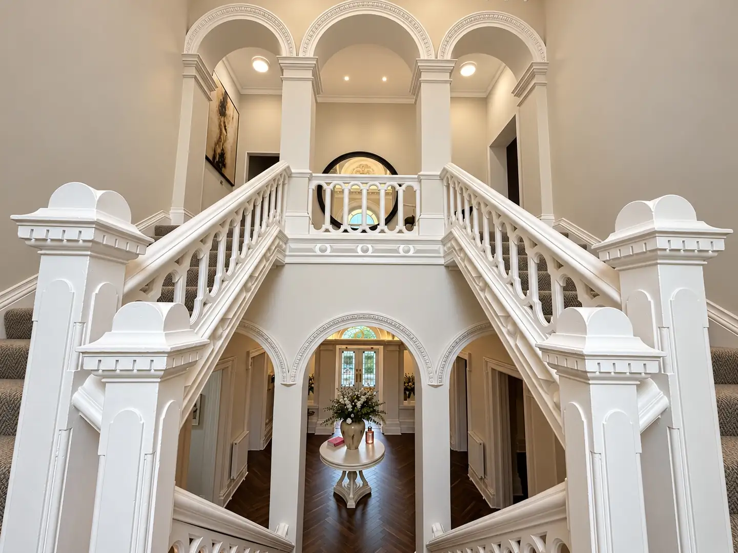 Double staircase with white balustrades looking down to the lobby