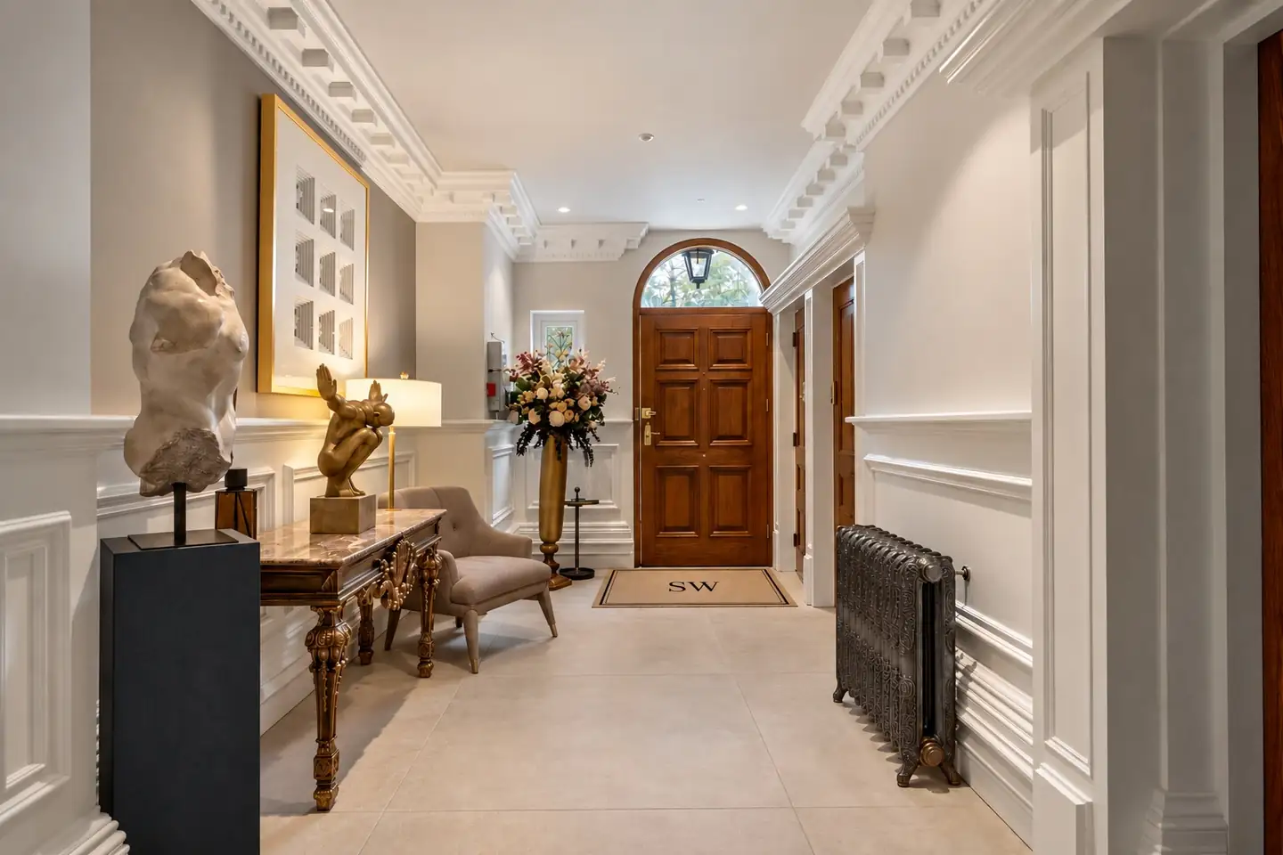 Panelled entrance lobby looking towards an arched front door with an SW doormat